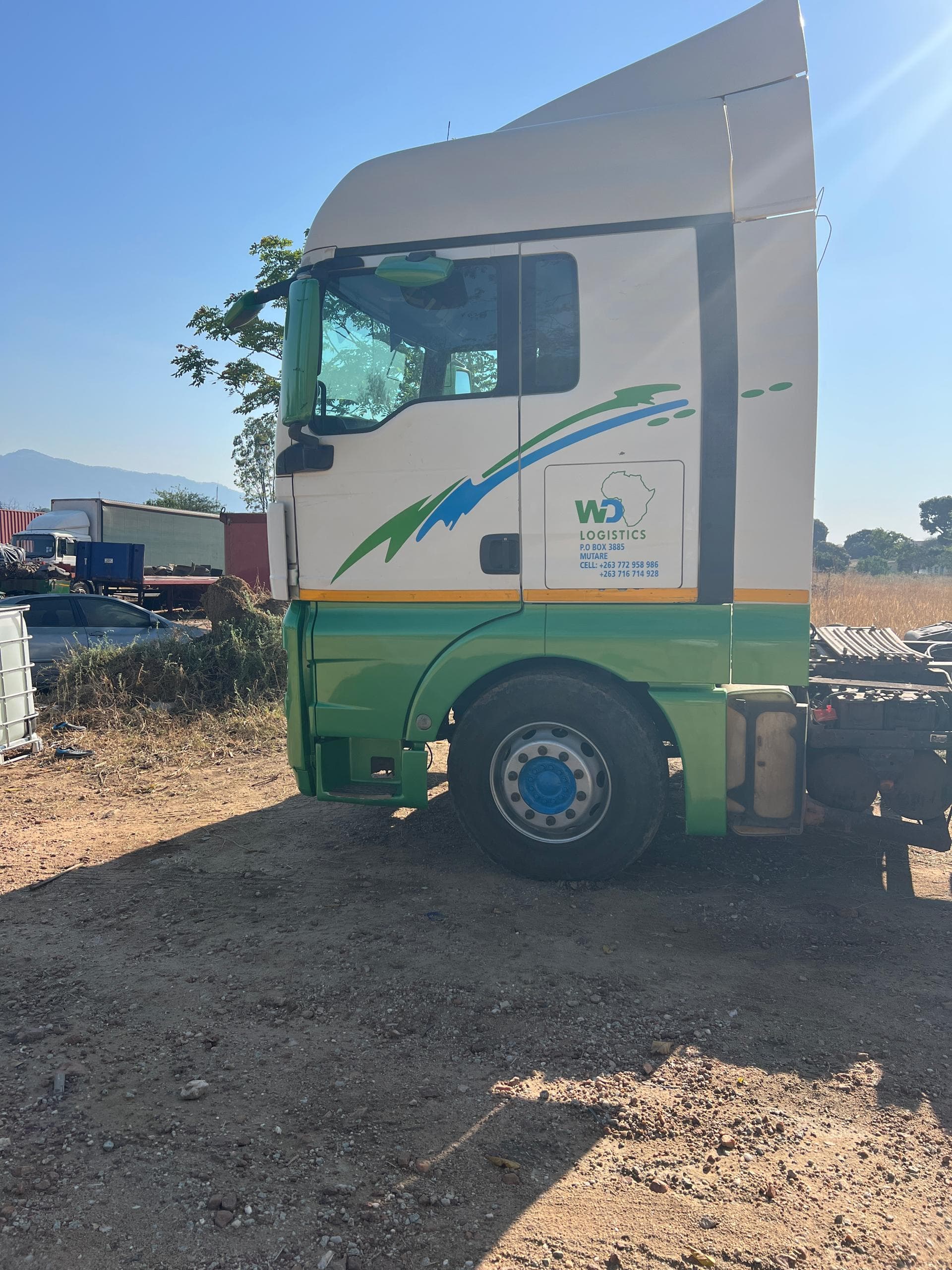 White and green WD Logistics MAN truck, side profile, parked in the yard