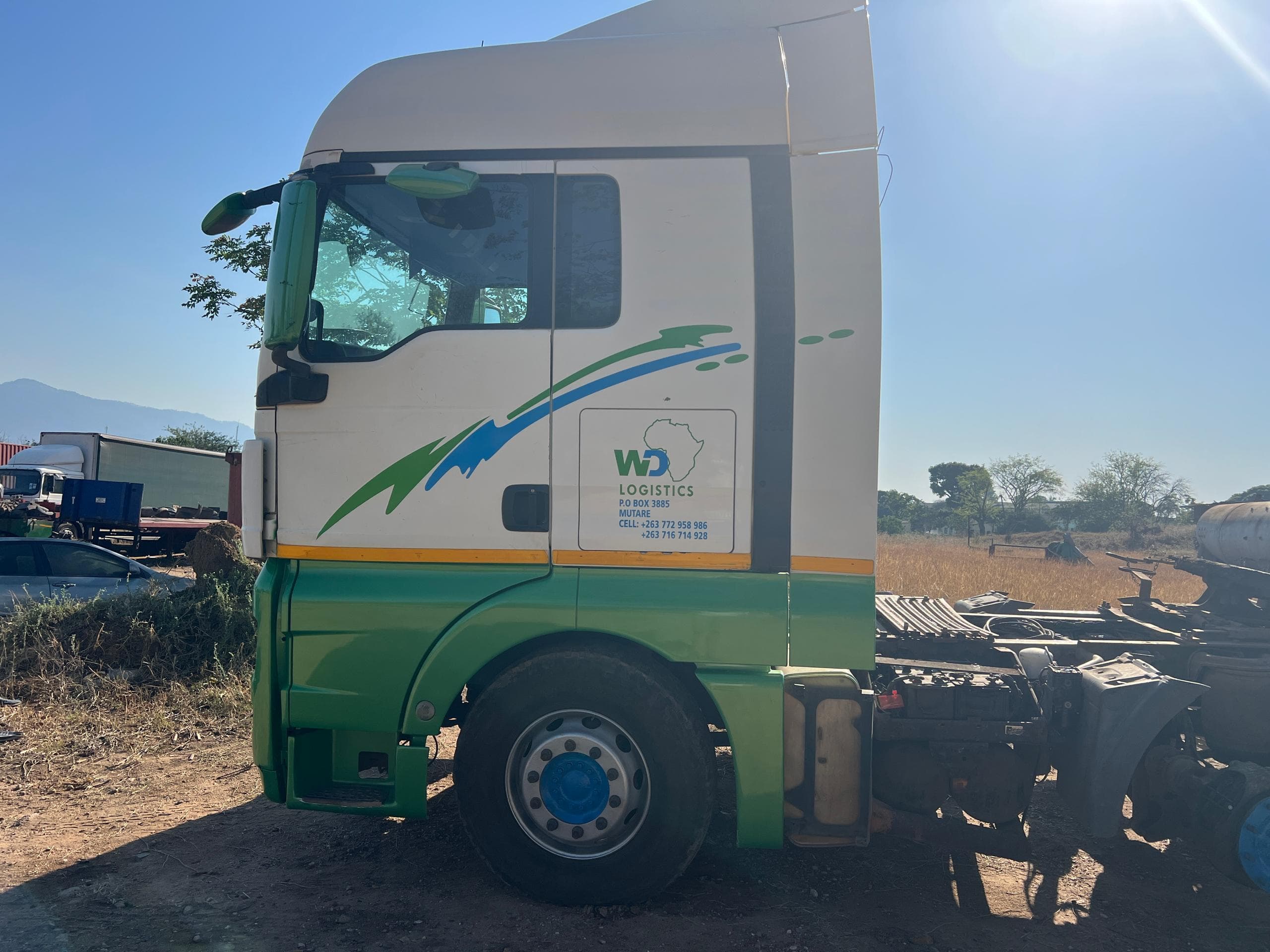 White and green WD Logistics truck, side profile, at the company yard